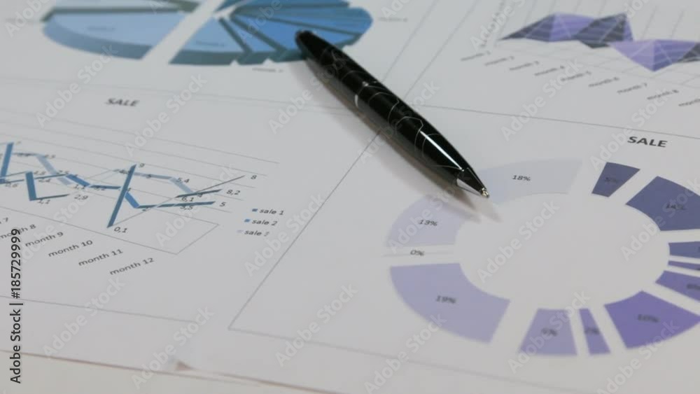 Close-up of the rotation of a black pen lying on colored diagrams. Close-up of the rotation of a black pen lying on colored diagrams.