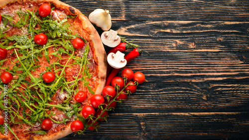Pizza Primavera. Cherry tomatoes, arugula, cheese. On a wooden background. Top view.
