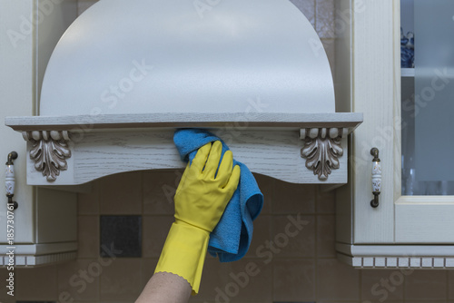 Women's hand in protective gloves wipes kitchen furniture with a blue rag. photo