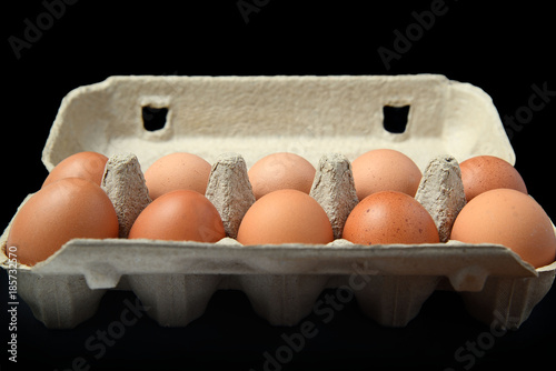 Десяток куриных яиц в упаковке на черном фоне вид сбоку