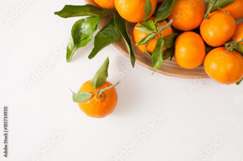 Fresh tangerines with green leaves on a white background © ekramar