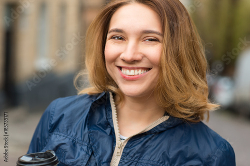 Happy young woman wearing blue raincoat 