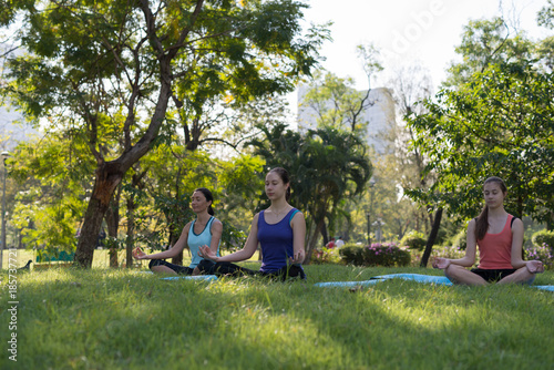 Activities in family, mother and daughter on a yoga mat to relax in the park outdoor, Concept of healthy lifestyle and relaxation..