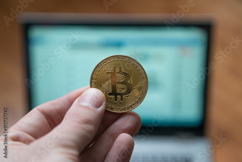 Man holding bitcoin in front of notebook computer