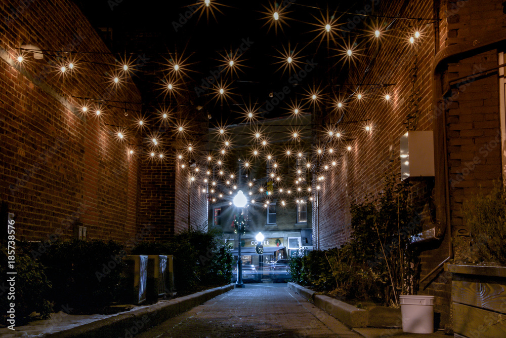 Exterior nighttime long exposure stock photo of electric lights hanging over alley in front of coffee shop in Cranford New Jersey in Union County on chilly December night