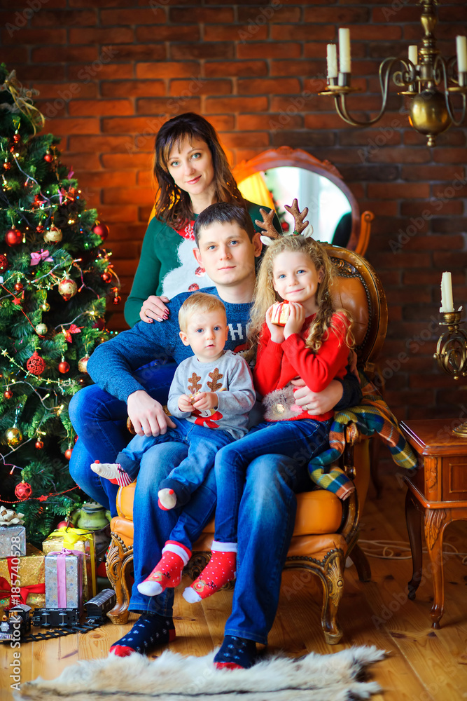 happy family in a room near a festive Christmas tree, sitting on a chair and embracing. happy family in a room near a festive Christmas tree, sitting on a chair and embracing.