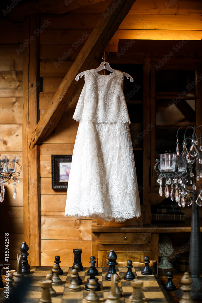 Wedding dress hanging on a hanger in a room over big chess