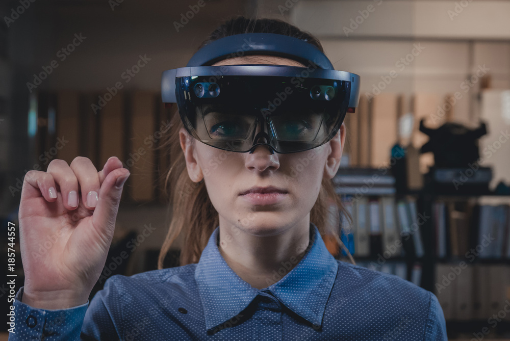 Portrait of young Caucasian female using augmented reality holographic hololens in modern office Portrait of young Caucasian female using augmented reality holographic hololens in modern office