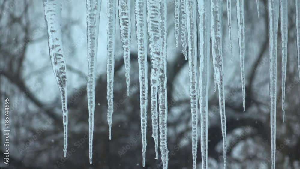 Large icicles outside the window and snow falling. Slow-mo Large icicles outside the window and snow falling. Slow-mo