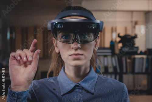 Portrait of young Caucasian female using augmented reality holographic hololens in modern office
