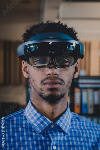 Portrait of young African American black male professional using augmented reality holographic hololens in modern office photo