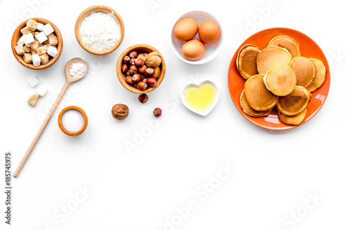 Cooking american pancakes. Ingredients, cakes, nuts and honey on white background top view copyspace