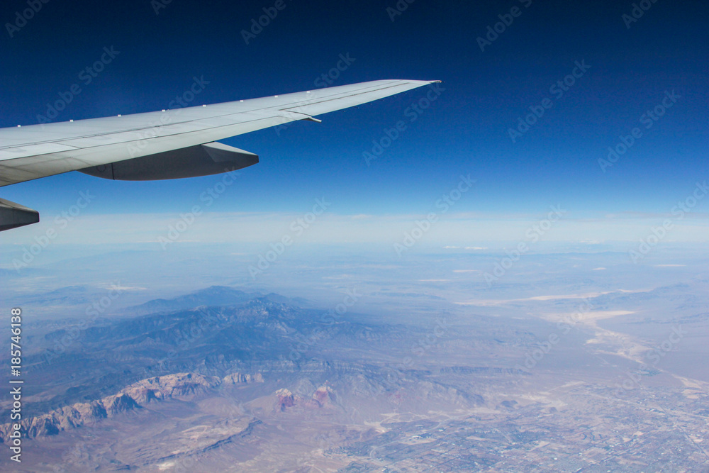 The view from a plane of the wing and the ground below with blue skies The view from a plane of the wing and the ground below with blue skies