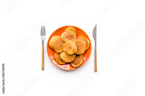 Pile of homemade pancakes on bright plate on white background top view copyspace photo