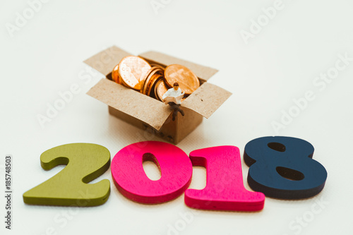 Miniature people, man sitting on box contain stack coin using as business, finance, bangking concept in year 2018 - Vintage filter photo