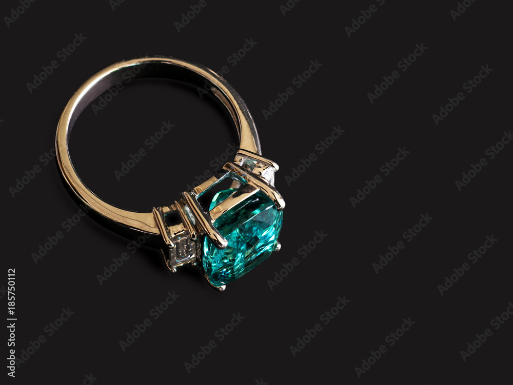 Closeup green gem ring with white diamond on black Closeup green gem ring with white diamond on black