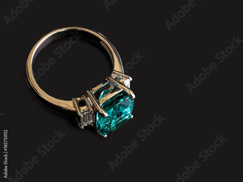 Closeup green gem ring with white diamond on black