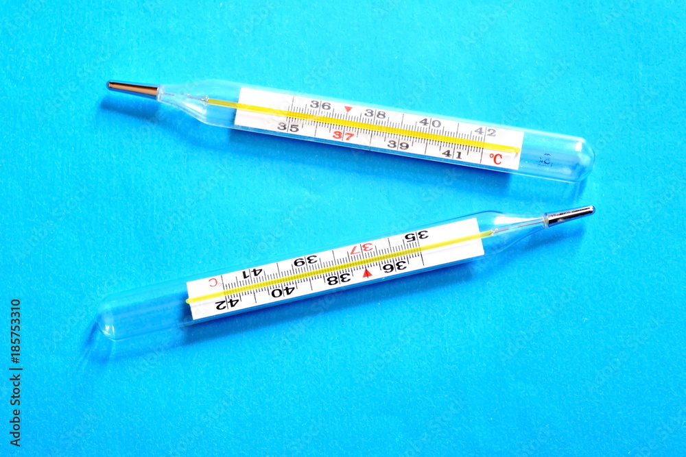 Two glass medical thermometer on blue background