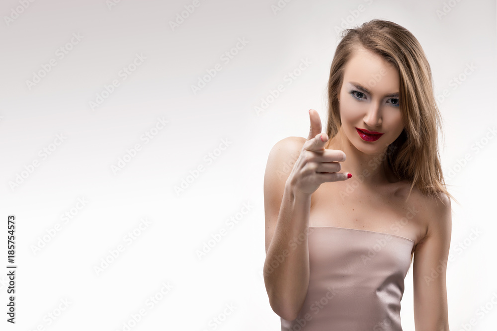The beautiful blonde red lips smiling girl points finger to you (the viewer). The beautiful blonde red lips smiling girl points finger to you (the viewer).