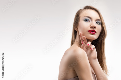 The beautiful blonde red lips smiling girl touches by fingers face and a neck and looks sideways