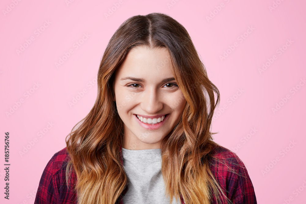 Cheerful pleasant looking female model has shining smile with perfect white even teeth, glad to recieve compliment from boyfriend, isolated over pink background. Happiness and beauty concept Cheerful pleasant looking female model has shining smile with perfect white even teeth, glad to recieve compliment from boyfriend, isolated over pink background. Happiness and beauty concept