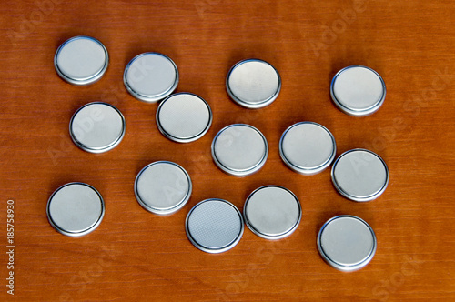 Rounded 3V battery cells on wooden table. photo