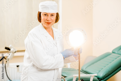 Portrait of a senior woman gynecologist in medical gown and hat preparing for procedure in the gynecological office