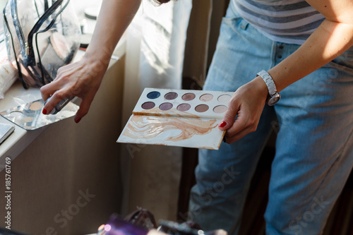 Female makeup artist with cosmetics at work close-up. Girl holding a white palette eyeshadow for makeup