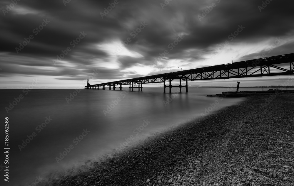 Seascape with jetty during a dramatic cloudy sunset