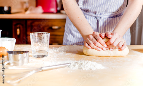 Woman's hands knead dough on a table, for the holiday