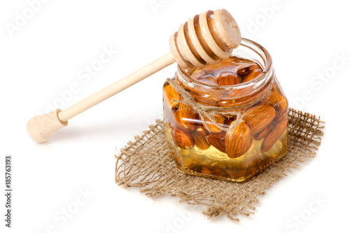 A honey jar with a spoon for honey nuts almonds