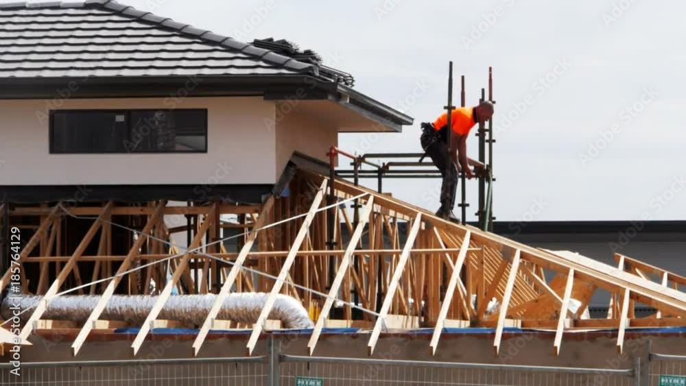 a worker removes the scaffolding from the roof of a new house construction site