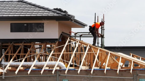 a worker removes the scaffolding from the roof of a new house construction site