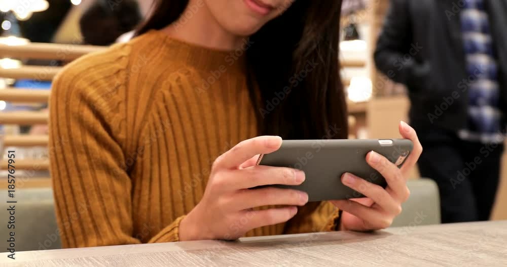 Woman playing game on cellphone in restaurant Woman playing game on cellphone in restaurant