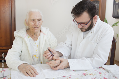Zabieg pielęgnacyjny dłoni bardzo starej kobiety. Pielęgniarz obcina paznokcie u rąk starej kobiecie. photo