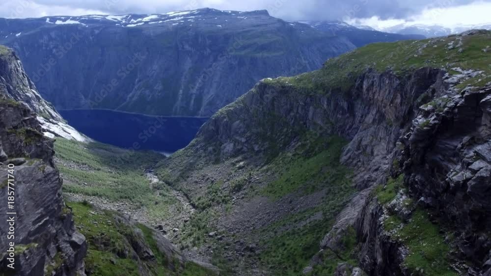 Aerial shot amazing view of nature Norwegian. Slow camera advance. Flight over high mountains with snowy peaks, dense green grass, mountain river. Typical nature of Norway, Europe in nice weather Aerial shot amazing view of nature Norwegian. Slow camera advance. Flight over high mountains with snowy peaks, dense green grass, mountain river. Typical nature of Norway, Europe in nice weather
