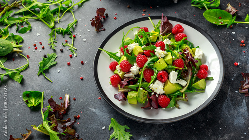 Fresh Tasty Raspberry salad with avocado, green vegetables, nuts, feta cheese, olive oil and herbs. healthy food.