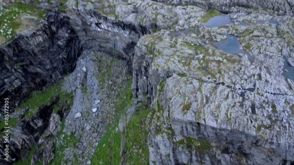 Slow flight by helicopter over beautiful mountainous terrain in sunny weather. Mountains with green grass, clear water in pond, camera turn from top to bottom. Water in the middle of the rocks Slow flight by helicopter over beautiful mountainous terrain in sunny weather. Mountains with green grass, clear water in pond, camera turn from top to bottom. Water in the middle of the rocks