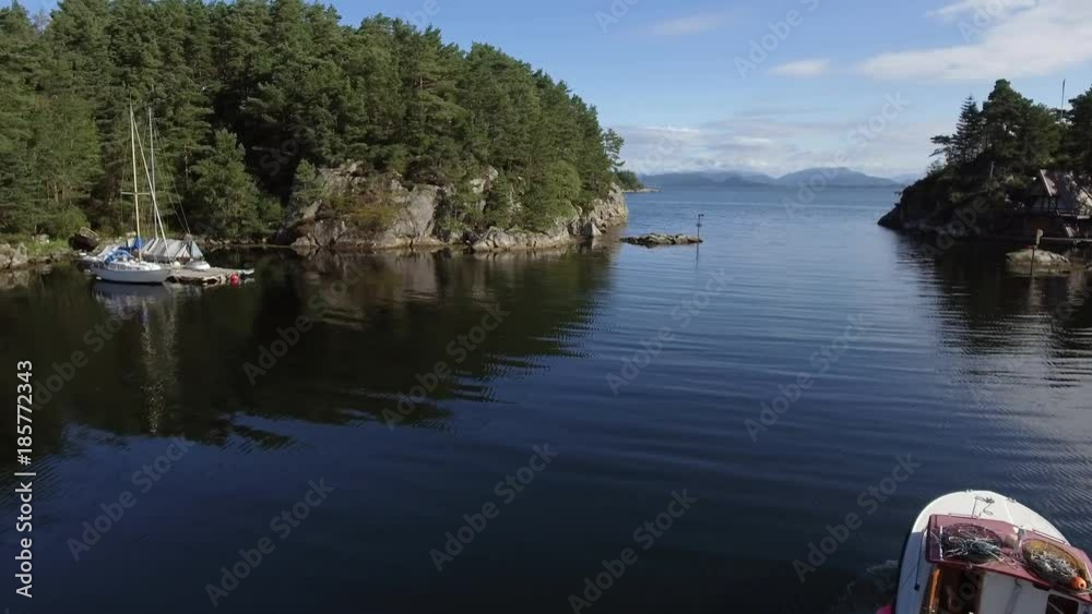 Aerial shot. High mountains and fluffy white clouds in the background. Beautiful white yachts in the port. Harbor is surrounded by rocks with a dense forest. Pure blue sea, magnificent sea landscape