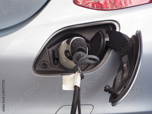 Electric Vehicle or EV car charging electric power in battery via EV charging socket and plug. Green energy concept.