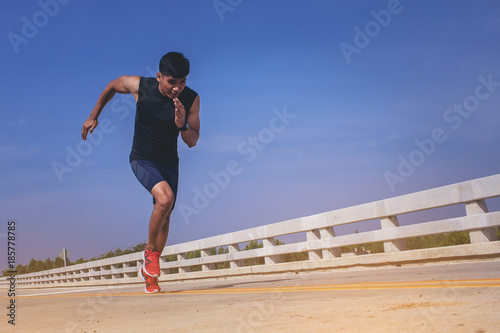 Man running sprinting on road. Fit male fitness runner during outdoor workout.