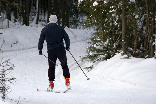 A skier in a light green jacket runs a distance in the forest
