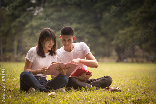 couple of high school students sit down and read a book in park, education concept © smilepoker