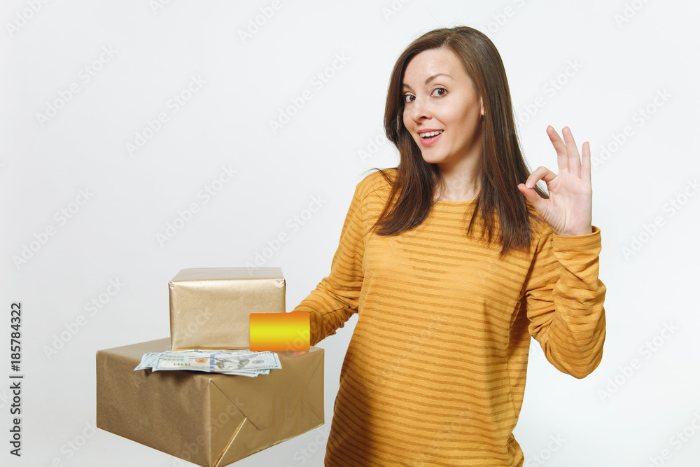 Pretty caucasian young birthday woman in yellow clothes holding credit card, cash money, golden gift boxes with present, celebrating holiday party, showing OK gesture on white background isolated. Pretty caucasian young birthday woman in yellow clothes holding credit card, cash money, golden gift boxes with present, celebrating holiday party, showing OK gesture on white background isolated.