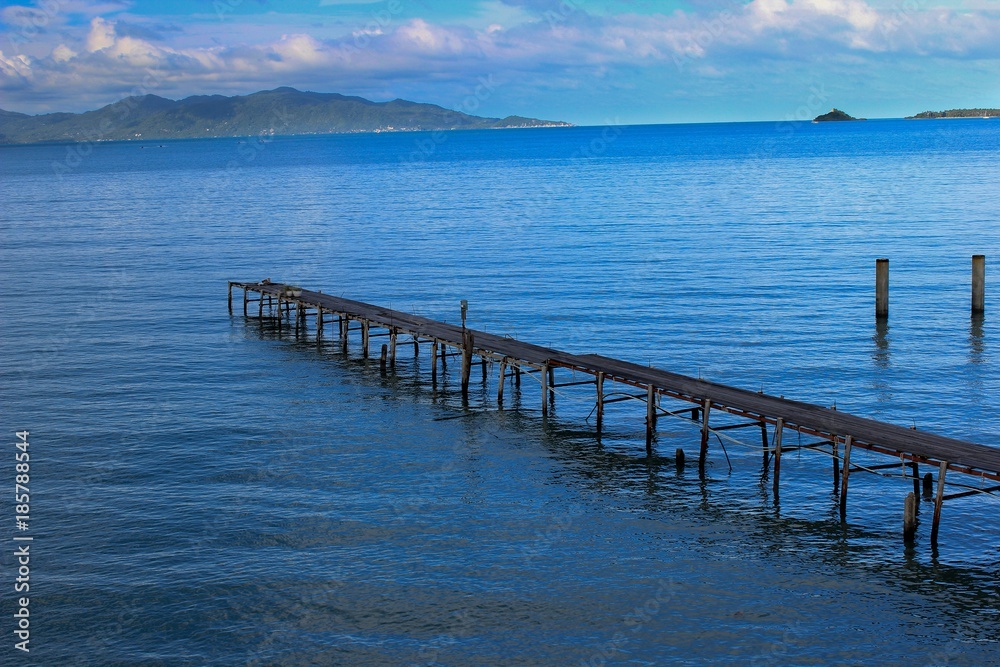 Blue Waters of Thailand with Cloudy Sky & a Wooden Walkway 