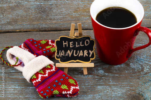 Concept HELLO january message on blackboard with a Cup of coffee and mittens