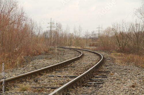 photo of railroad leading through the autumn landscape with bare trees