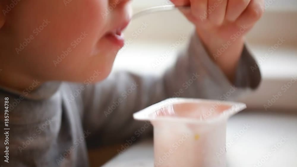 video child eats yogurt with a spoon sitting at the table video child eats yogurt with a spoon sitting at the table