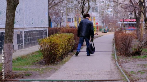 A drunk man staggers, walking along the road in the city, goes unstable gait. 
