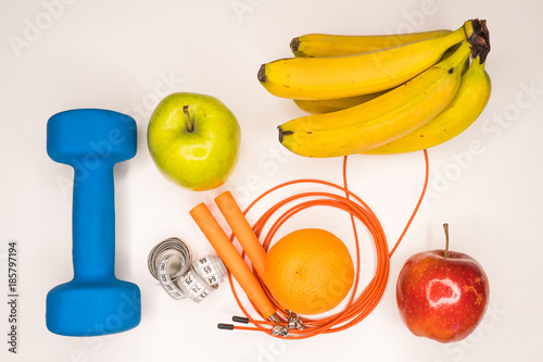 healthy eating concept. Dumbbell, rope, bananas, orange, measuring tape waist, oranges, red apple, green apple, on a white table. healthy lifestyle. sport. Fitness diet